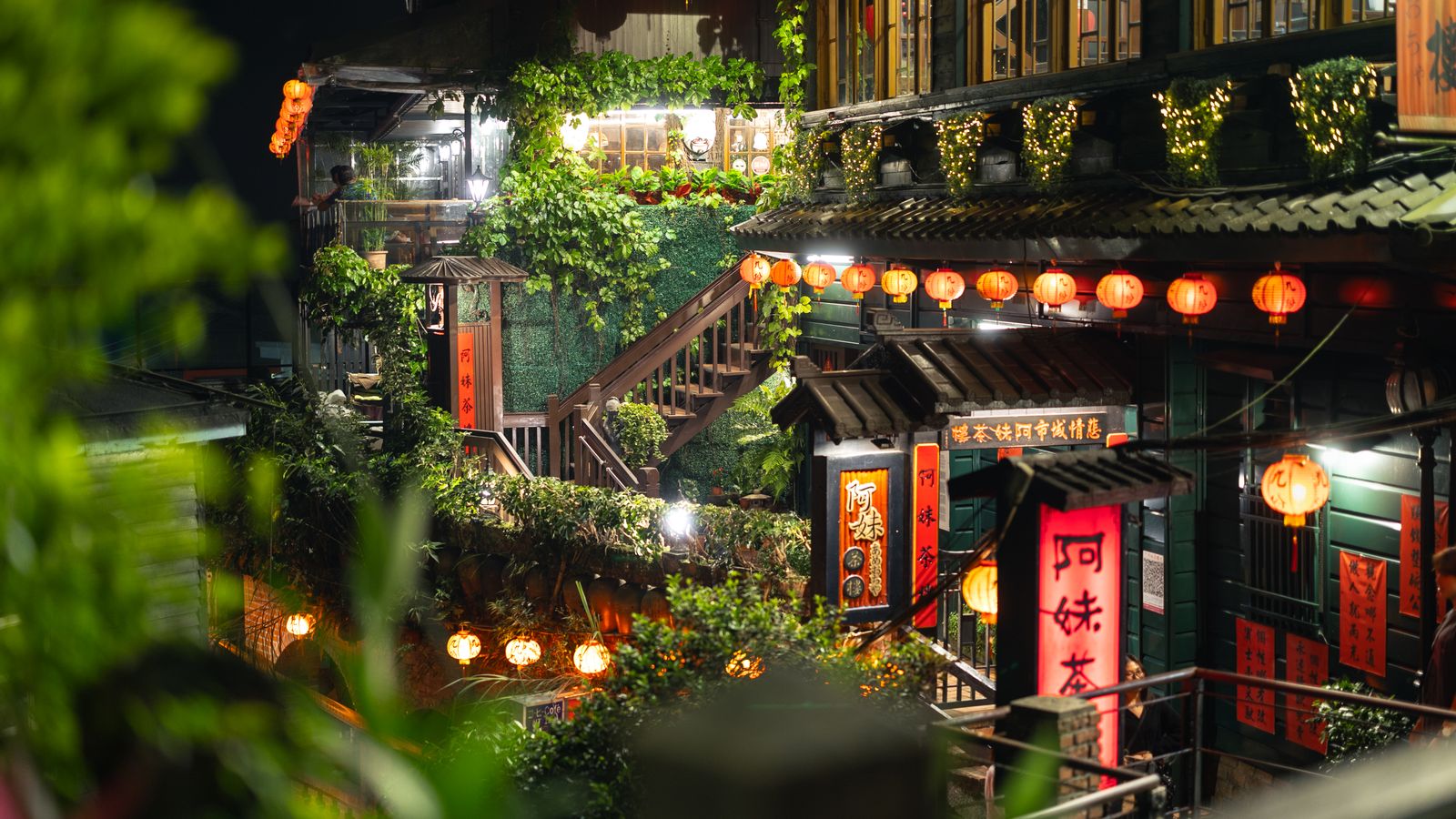 A lantern-lit Jiufen tea house surrounded by green hills