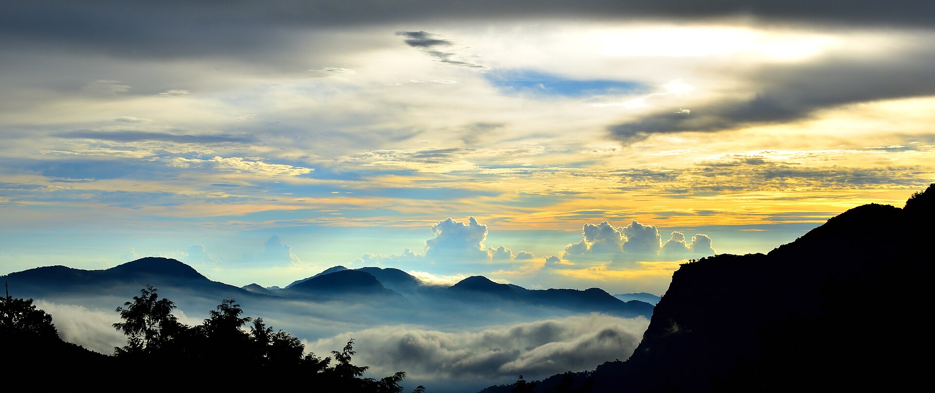 A golden sky above dark mountain ridges and a glowing sea of clouds in Alishan